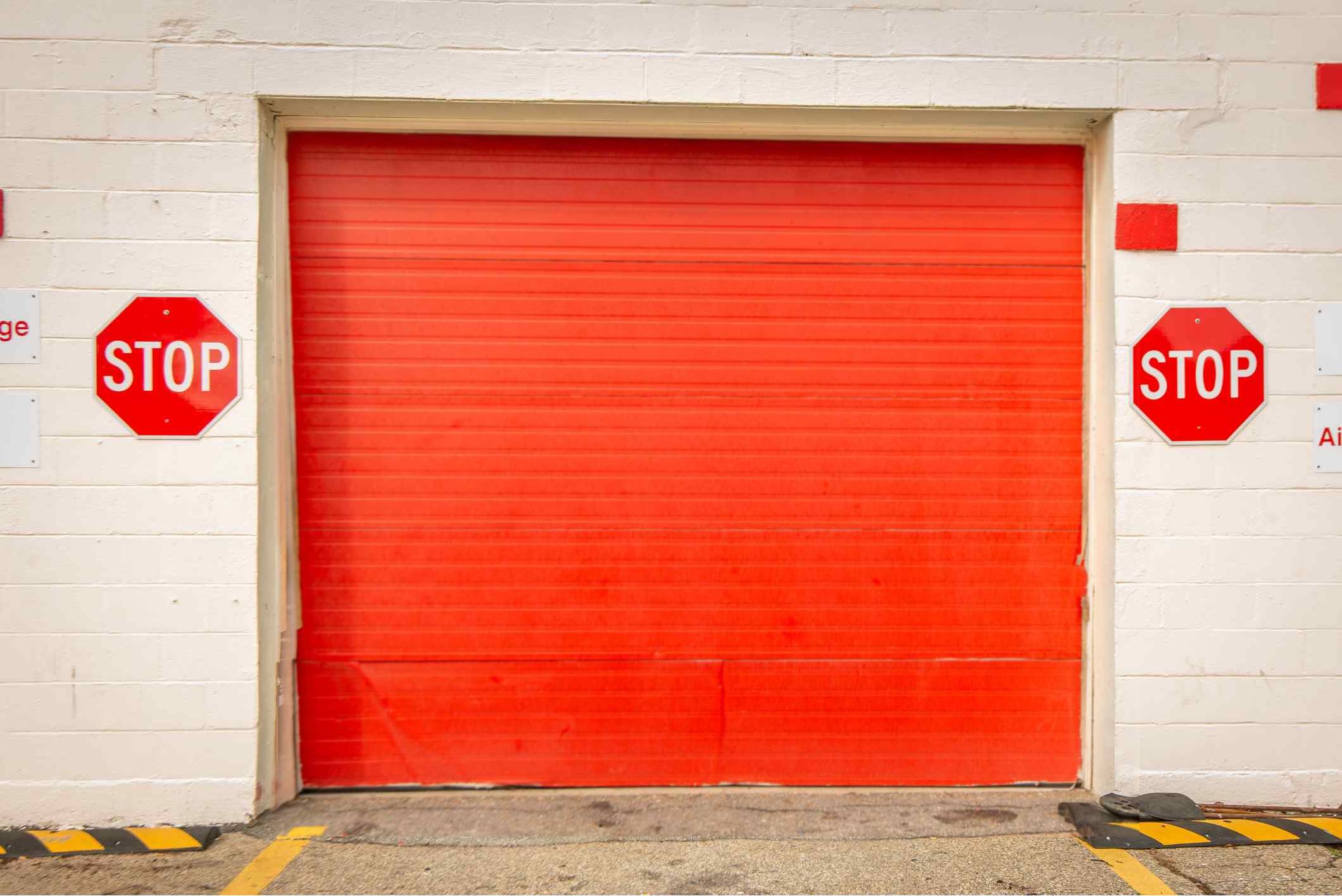 A red garage door in front of a white wall.