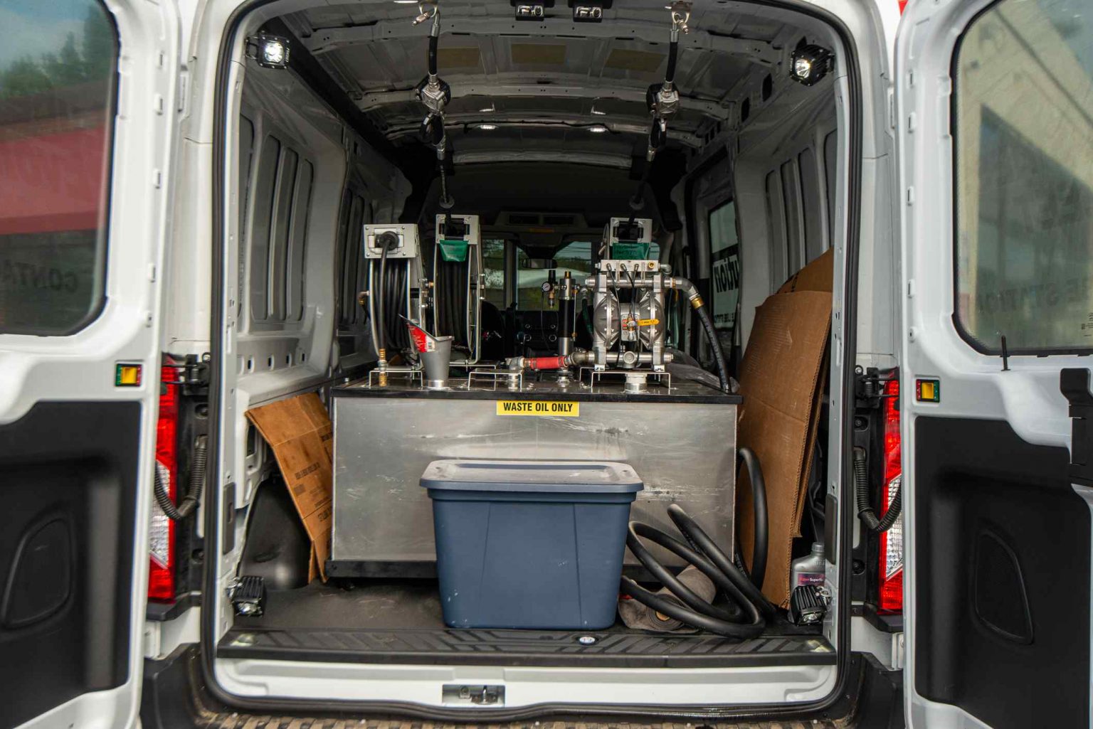 A van with the back door open and the rear compartment filled with tools.