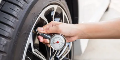 A person is checking the tire pressure of their car.