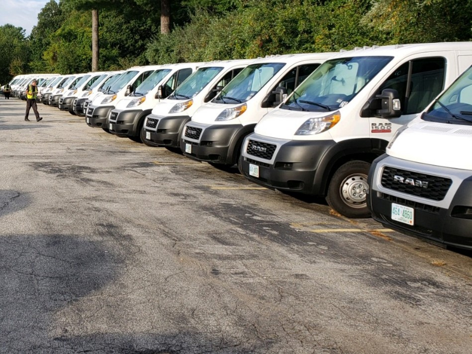 A row of white vans parked in a parking lot.